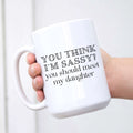A white ceramic coffee mug with the text You Think I'm Sassy? You Should Meet My Daughter printed in black font.
