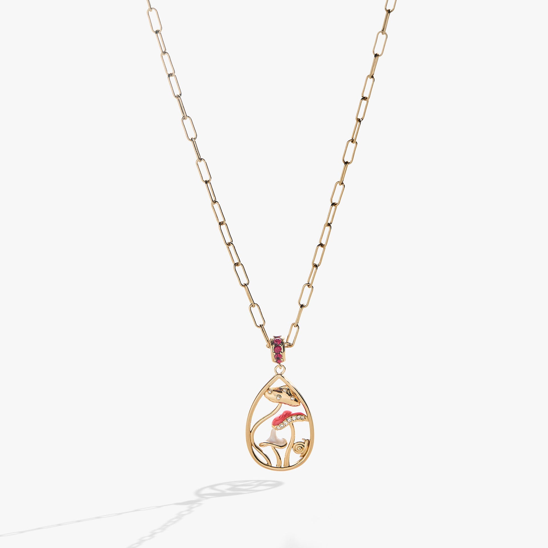 Gold circle pendant necklace featuring whimsical mushroom charms and a ruby-red crystal accent ring