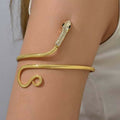 Close up of a golden brass snake-shaped arm cuff on a model's arm