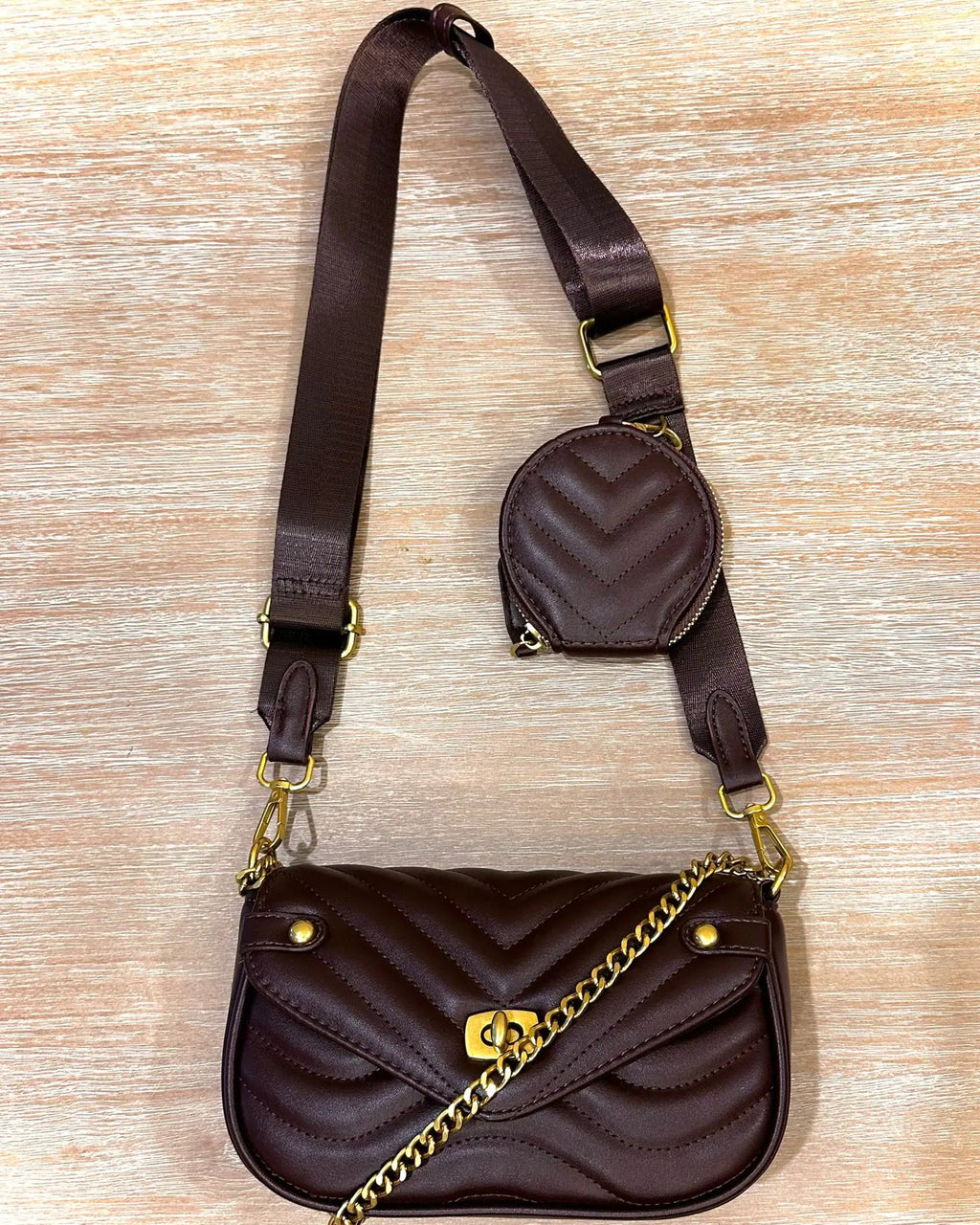 Brown quilted handbag with matching round pouch on a wooden surface