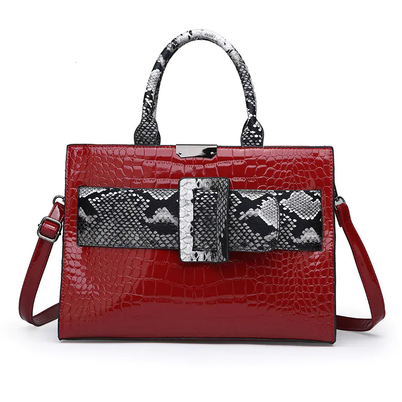 Women's handbag featuring a red crocodile-embossed texture with a snake pattern center strip and large buckle detail.