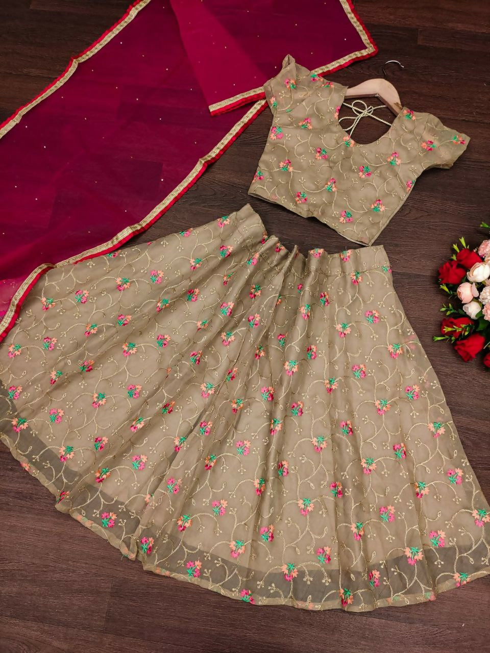 A beige organza silk lehenga choli for girls with floral-inspired embroidery.