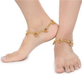 Close up of gold-polished traditional Indian payal foot chain on a woman's ankle.