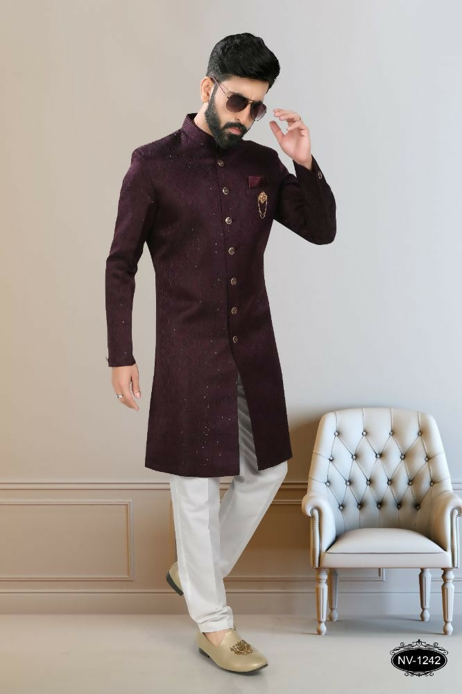 A handsome boy wearing a wine-colored kurta with intricate sequence embroidery and white pyjamas.