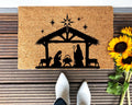 Minimalist Nativity design hand-painted on a natural tan coir doormat for outdoor entryway use.