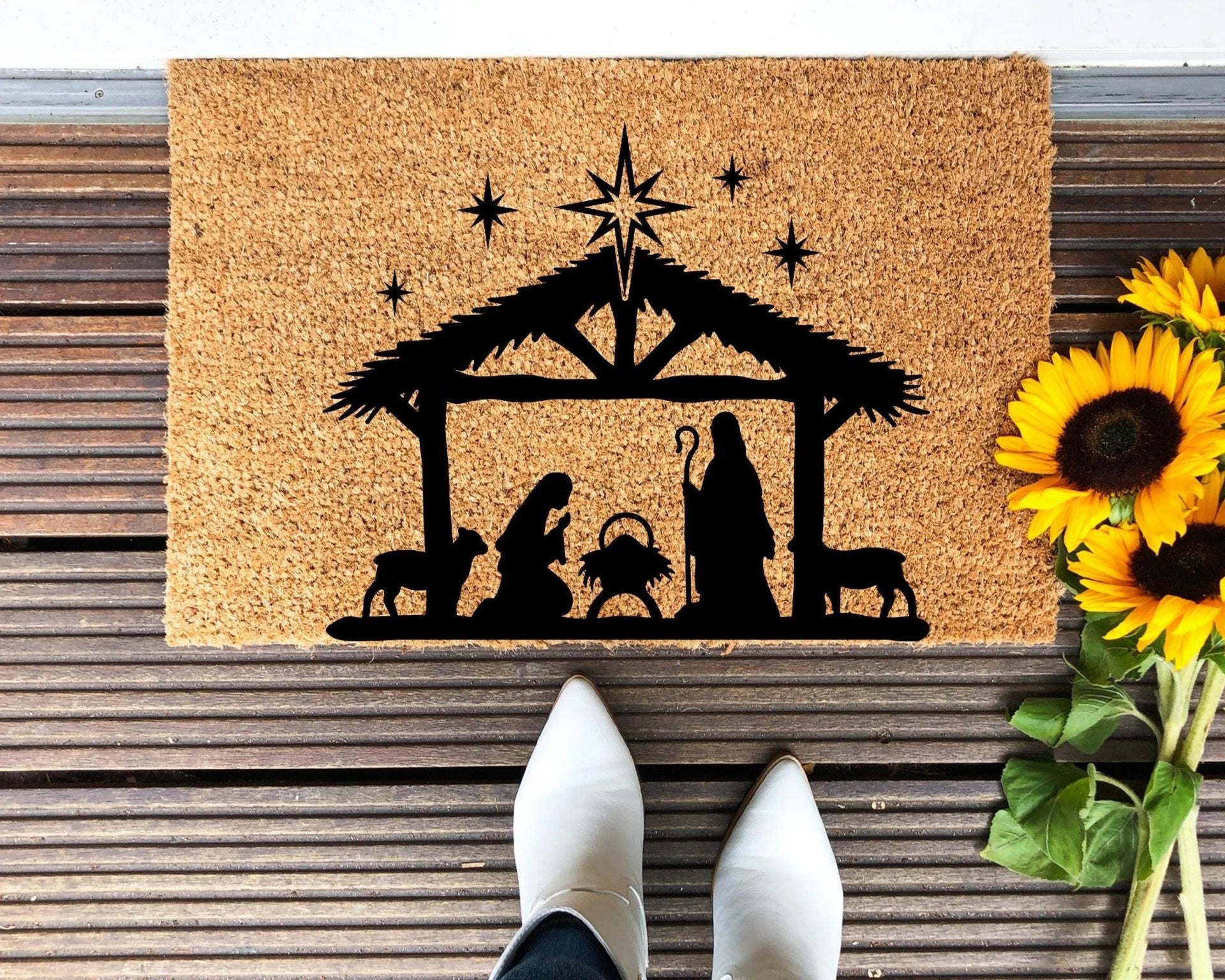 Minimalist Nativity design hand-painted on a natural tan coir doormat for outdoor entryway use.