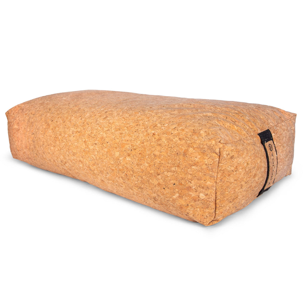 A sustainable cork bolster in natural cork brown resting in a minimalist living room setting.