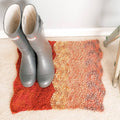 Finished crochet rug featuring a natural wave stitch pattern lying on a wooden floor.