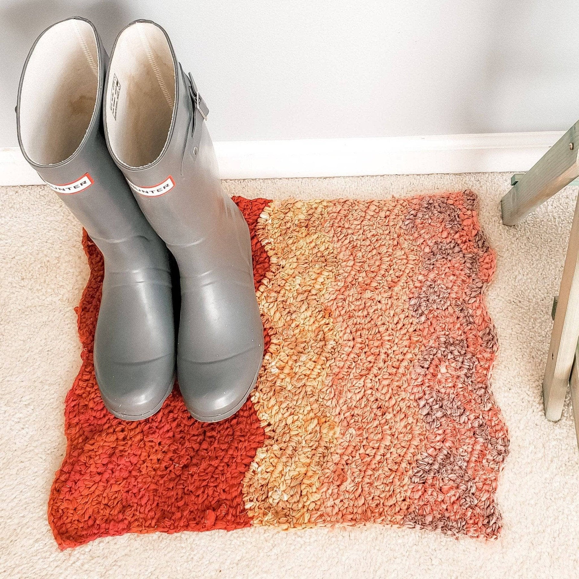 Finished crochet rug featuring a natural wave stitch pattern lying on a wooden floor.