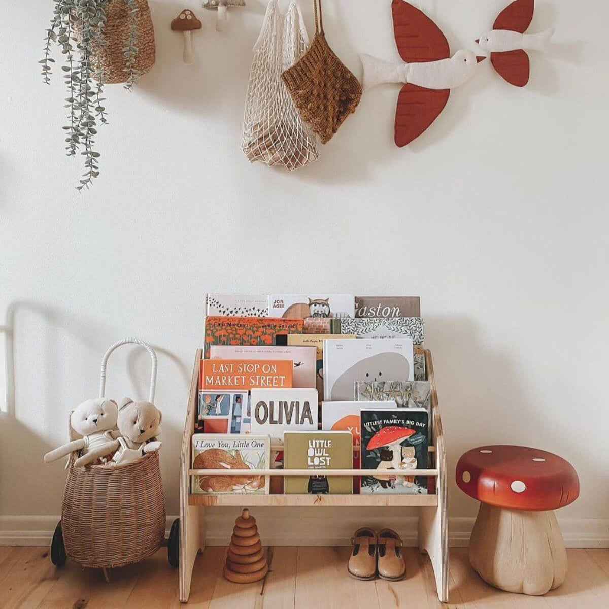 Minimalist white and natural wood Montessori bookshelf filled with children's books.