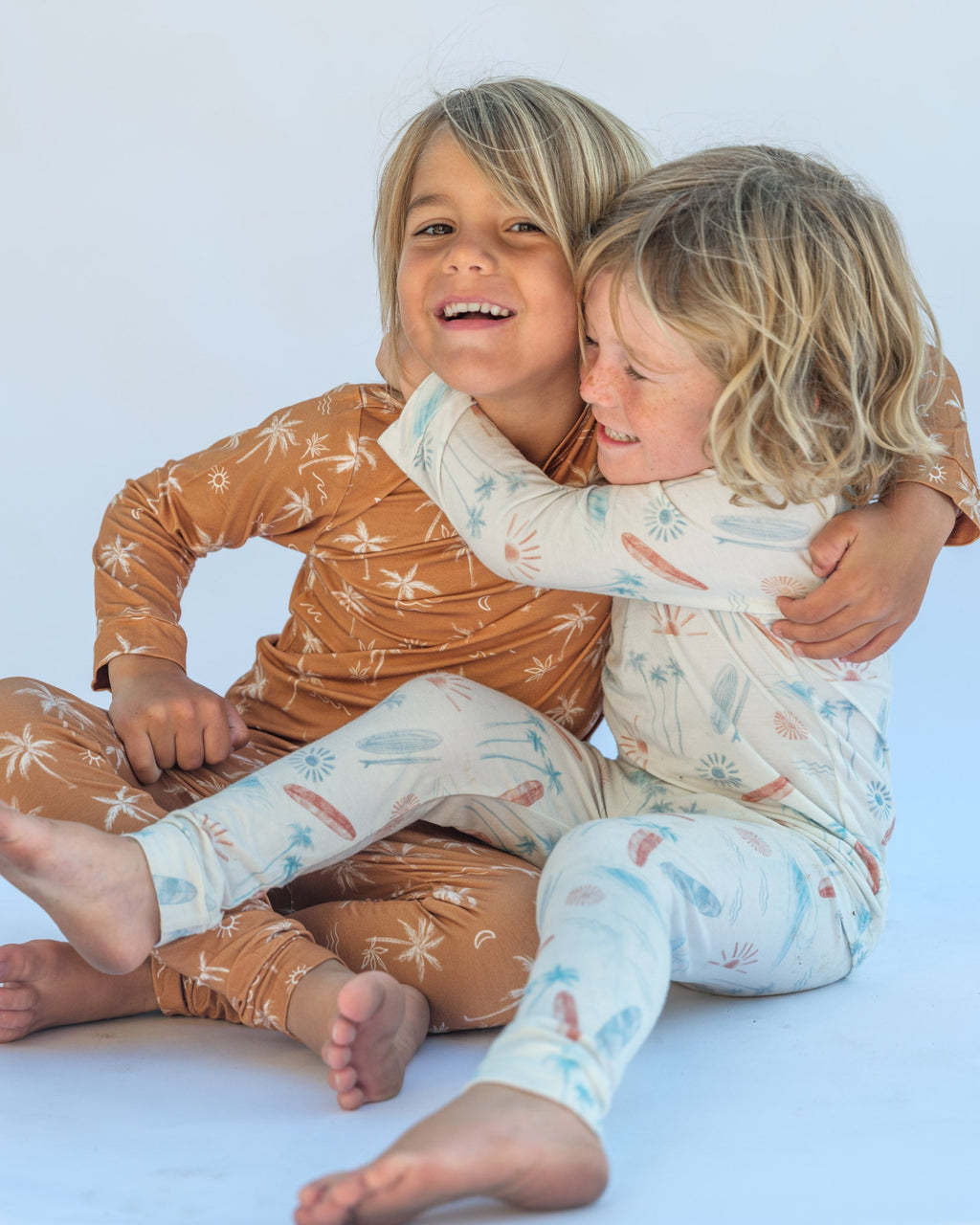 Two children in matching pajamas sitting on a light blue background
