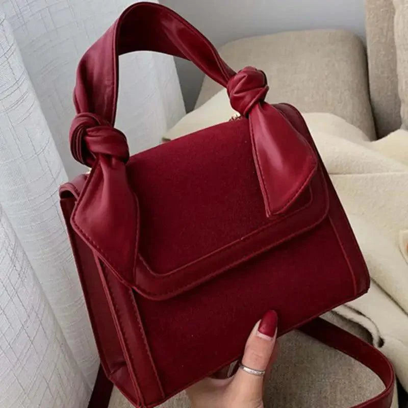 Classic designer shoulder bag featuring genuine suede panels, circular ring hardware, and a luxury metal pendant.