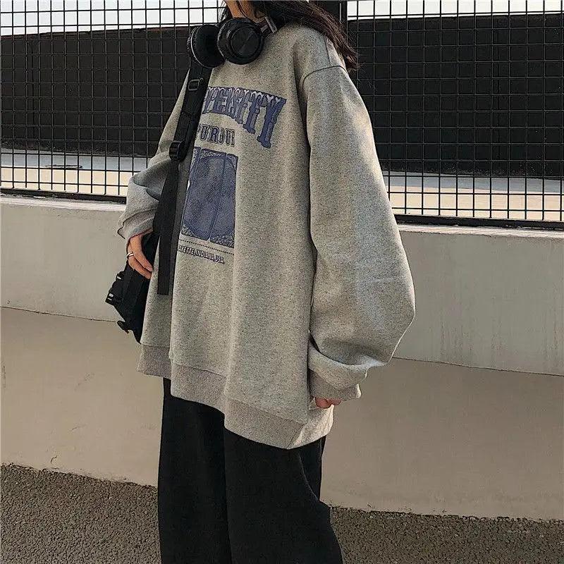 Woman wearing an oversized vintage collegiate sweatshirt with embroidered retro lettering in soft knit fabric.
