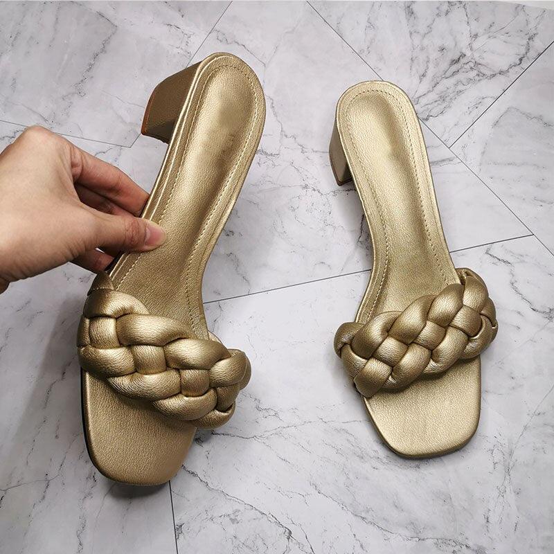 Top-down view of woven square-toe women's flat slides in a casual outdoor setting