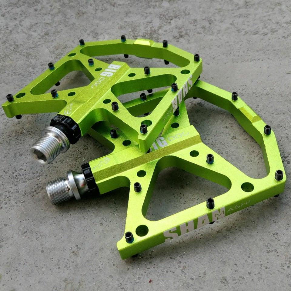 A pair of ultralight aluminum mountain bike pedals available in green, black, and red.