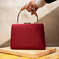A sleek maroon synthetic fabric evening clutch in a compact rectangular shape