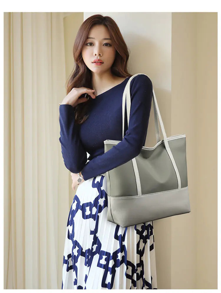 A woman carrying a grey two-tone large capacity tote shoulder bag.