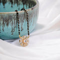 Close up of a Gold Tone AD Mangalsutra necklace featuring intricate traditional design on a white background.
