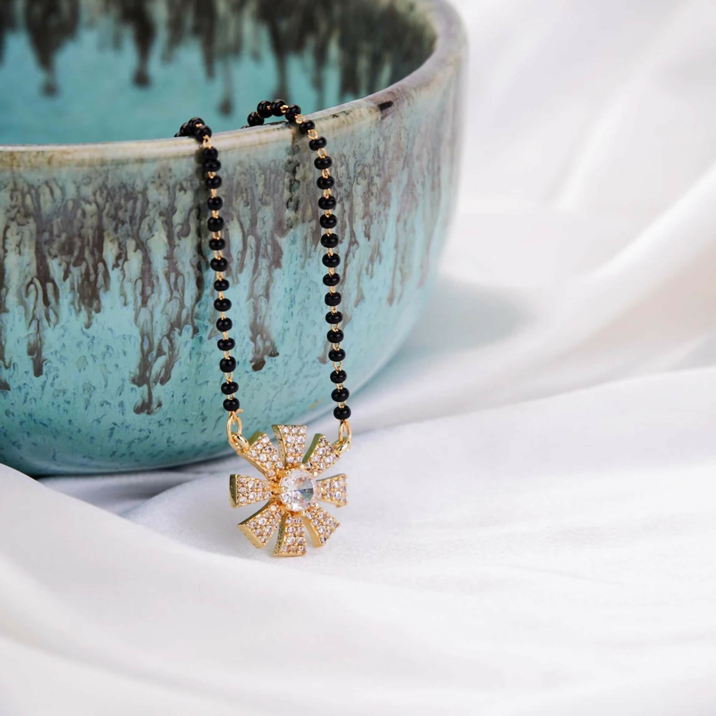 Close up of a Gold Tone AD Mangalsutra necklace featuring intricate traditional design on a white background.