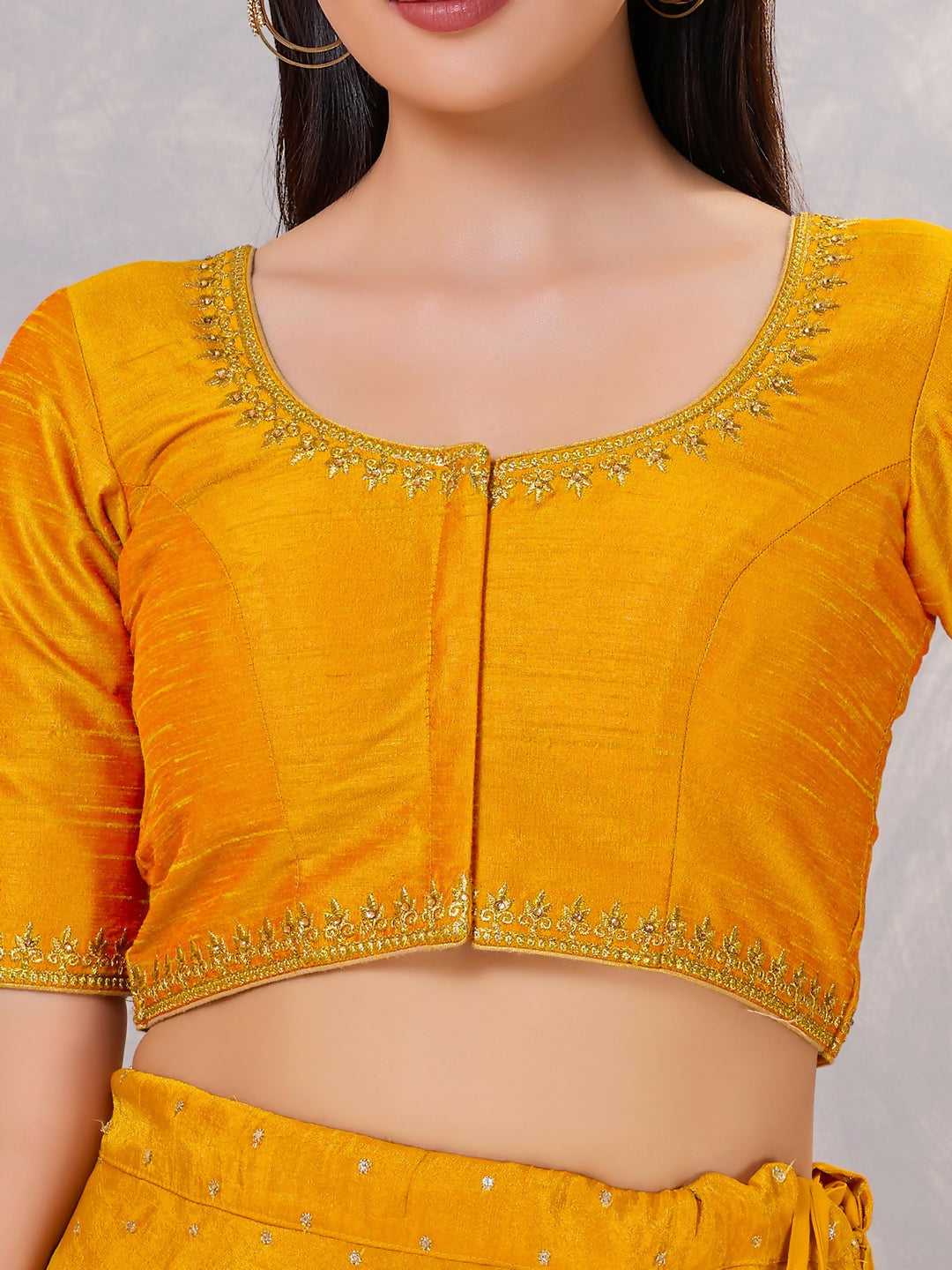 Close-up of mustard silk stitched blouse with intricate embroidery and round neck