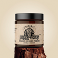 A 4oz jar of Johnny Slicks Original Organic Oil Based Pomade with a black lid, set on a natural wood stump.