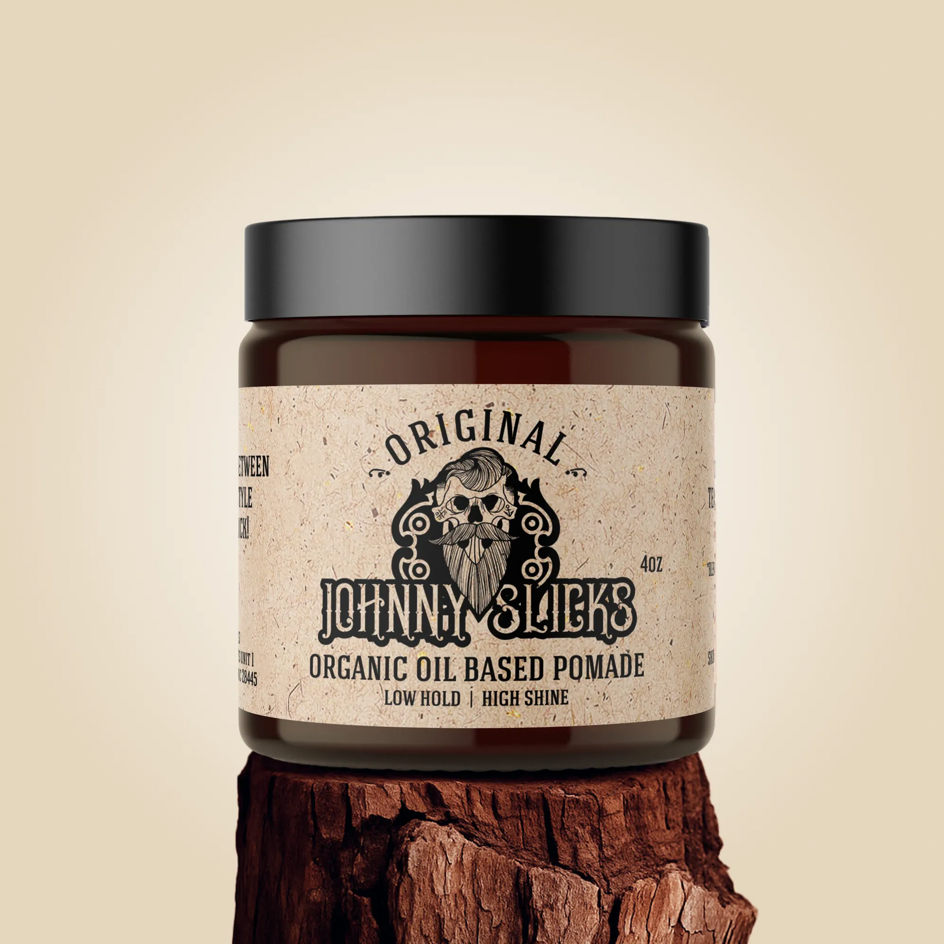 A 4oz jar of Johnny Slicks Original Organic Oil Based Pomade with a black lid, set on a natural wood stump.