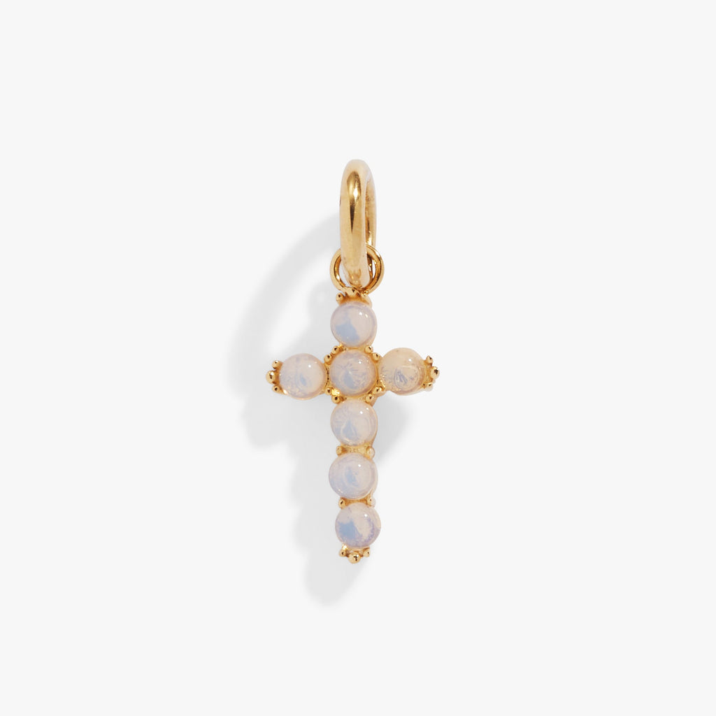 Close up of an iridescent opal cross charm in gold and silver stainless steel.