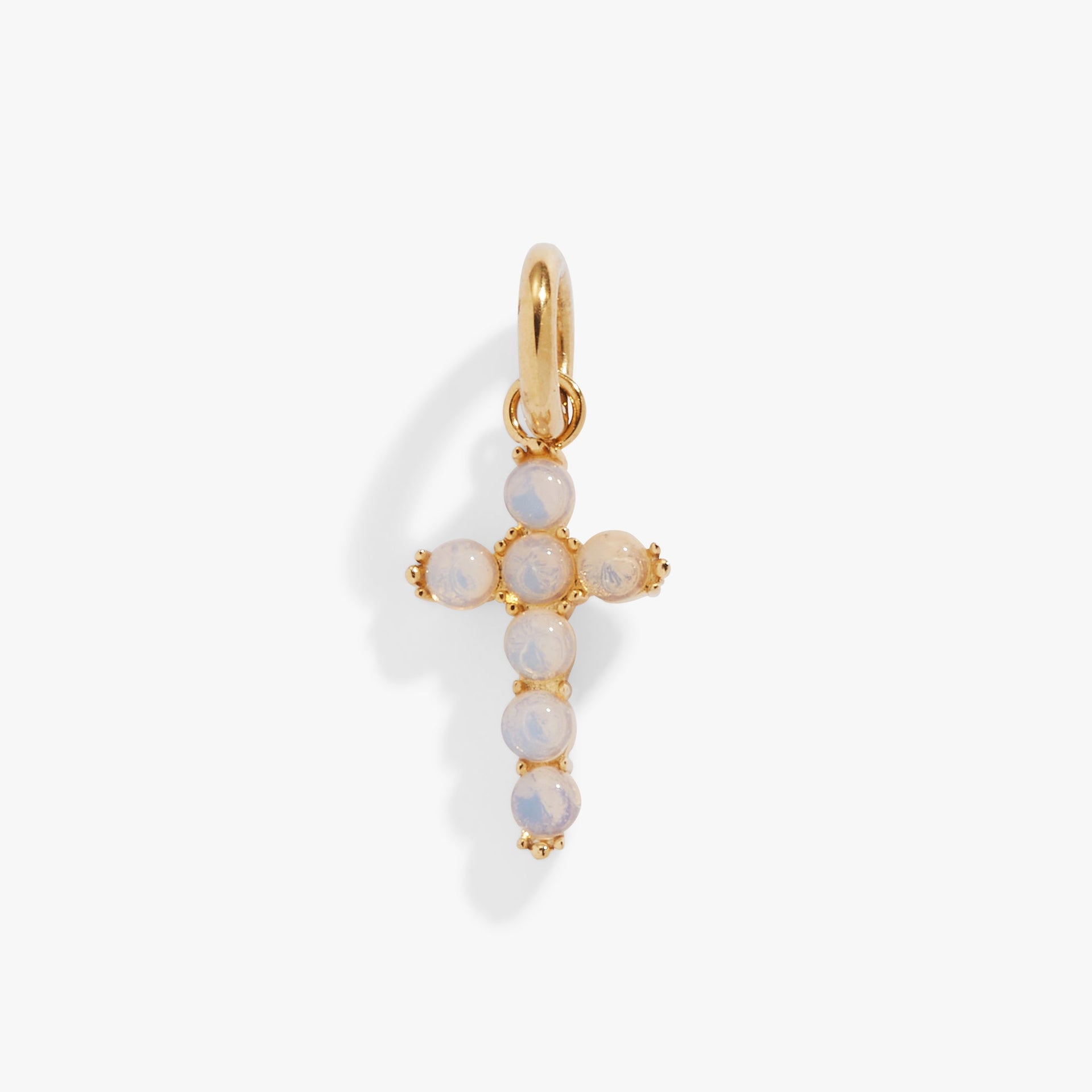 Close up of an iridescent opal cross charm in gold and silver stainless steel.