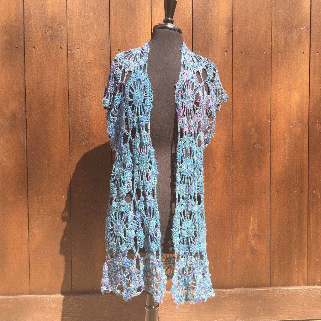 A handmade openwork lace duster crochet cover-up styled as a breezy summer layer.