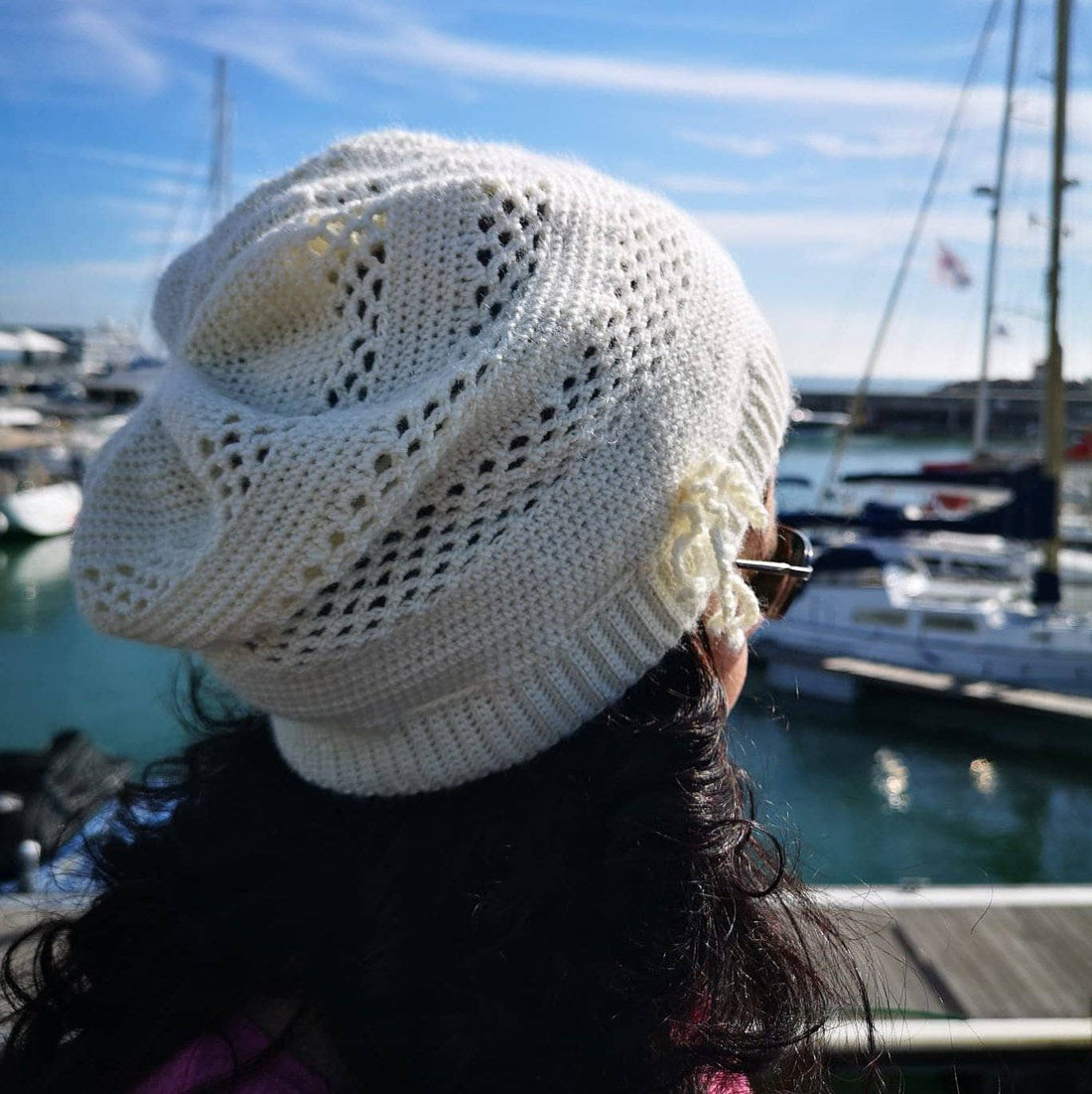 A close-up of a creamy off-white crochet beanie with a relaxed, bohemian-style texture.