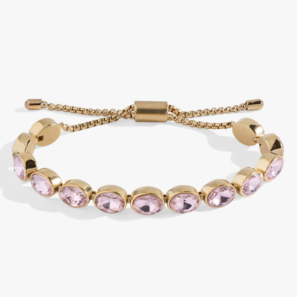 Polished gold-tone tennis bracelet with oval pink crystals and an adjustable bolo slider clasp.