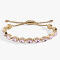 Polished gold-tone tennis bracelet with oval pink crystals and an adjustable bolo slider clasp.