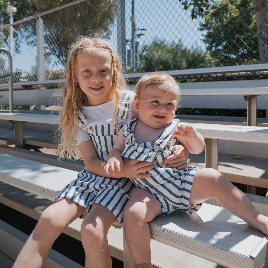 Toddler wearing blue and white nautical striped denim overalls with buckle details