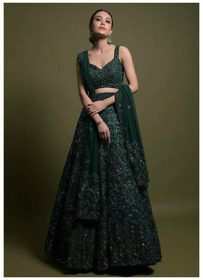 A luxurious dark green net lehenga choli set featuring intricate dori, sequins, and thread embroidery work.