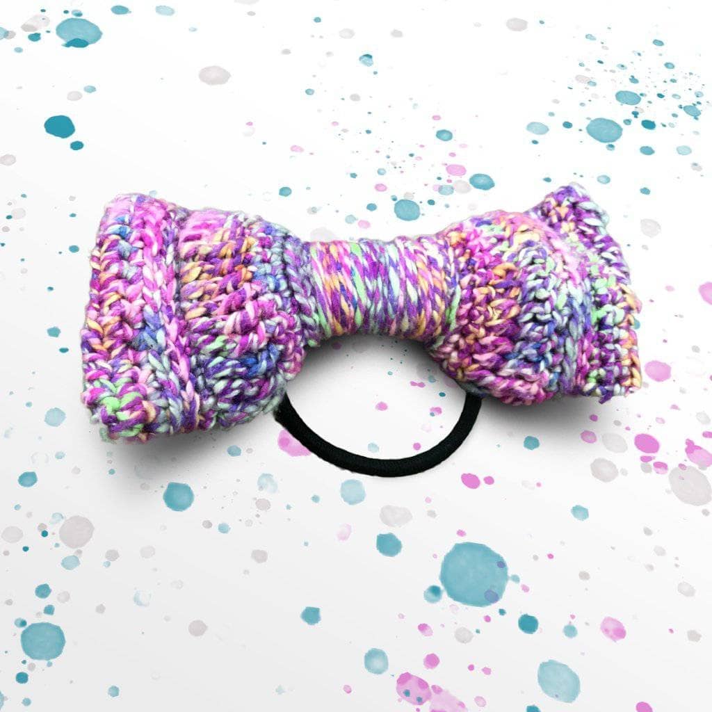 Crochet bow tie in vibrant purple, pink, and lime green variegated yarn on a white background.