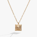 Gold ravioli shaped locket pendant necklace with red enamel tomato detail on a cable chain.