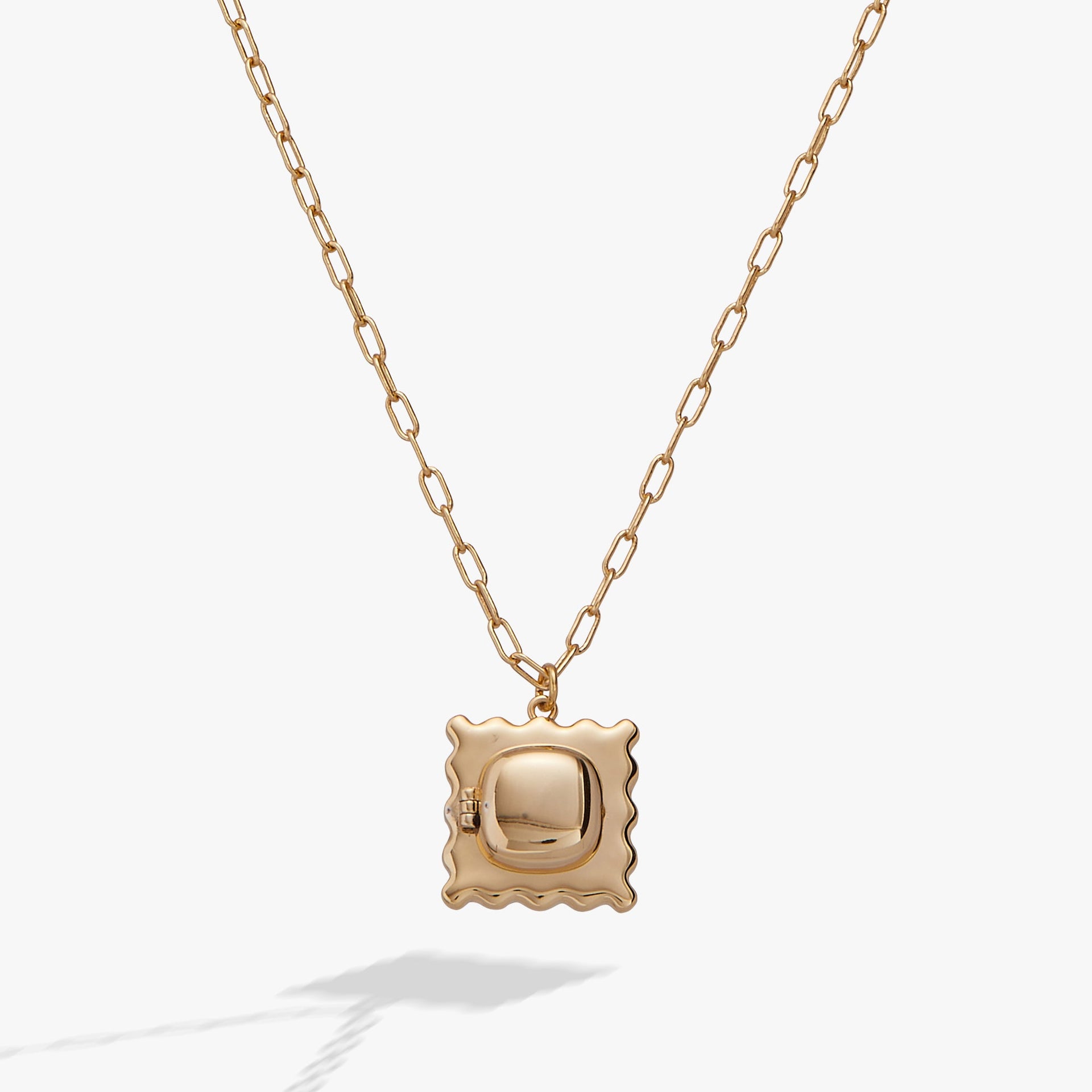 Gold ravioli shaped locket pendant necklace with red enamel tomato detail on a cable chain.
