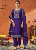 Woman wearing a vibrant violet silk blend A-line salwar suit with intricate gold embroidery and three-quarter sleeves.