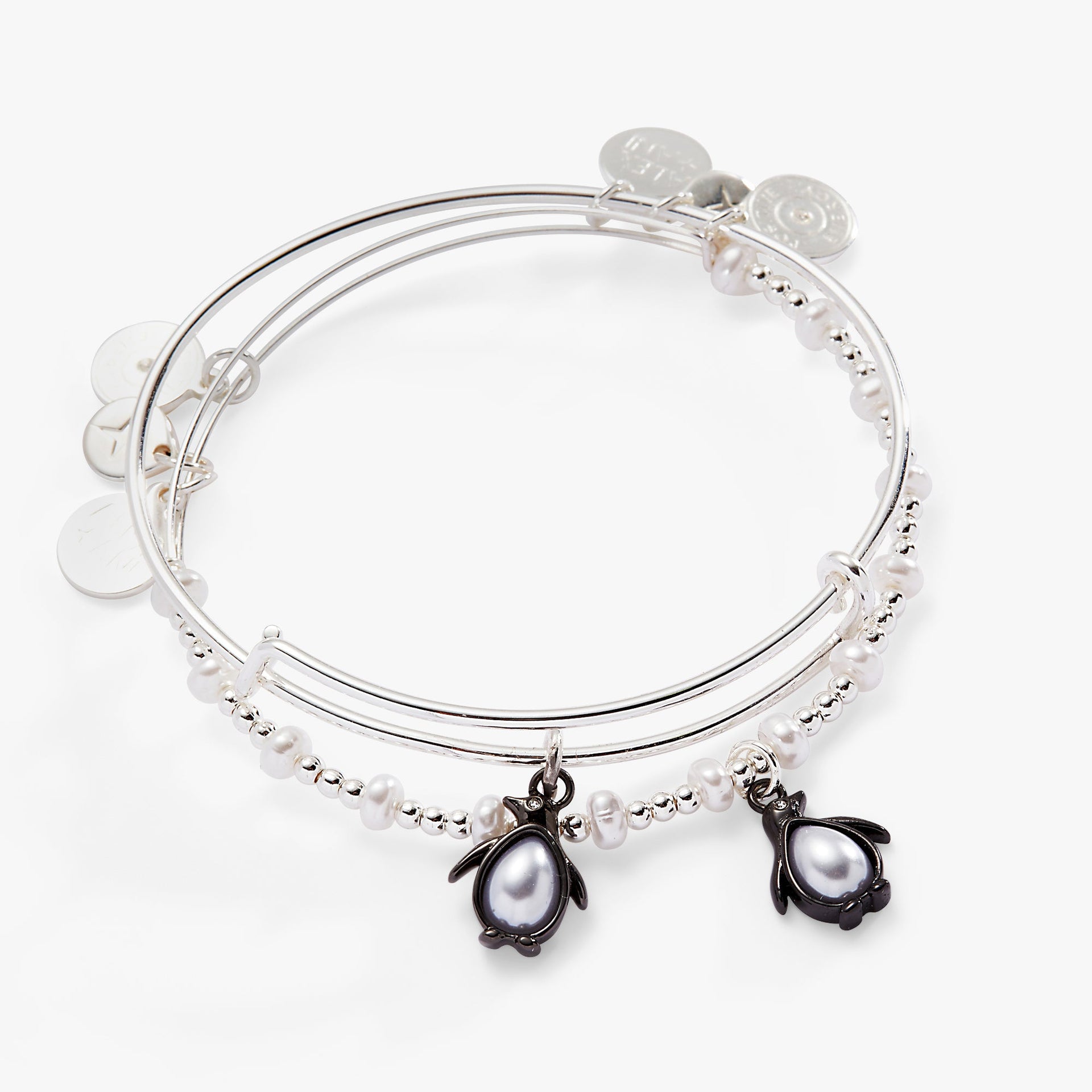 Set of two silver-tone bangles featuring enamel and pearl crystal penguin charms with accent beads.