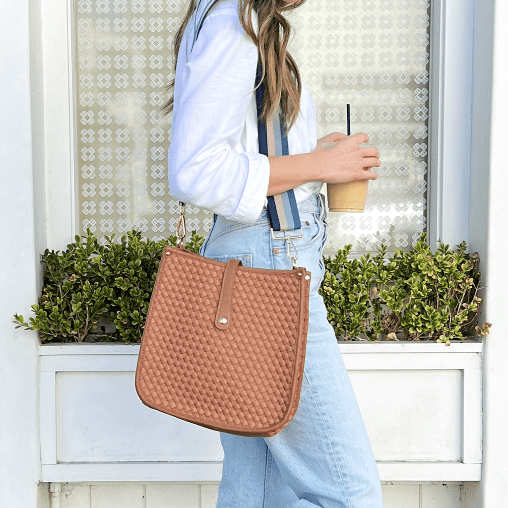 Woman carrying a brown woven neoprene courier bag with a striped interchangeable strap