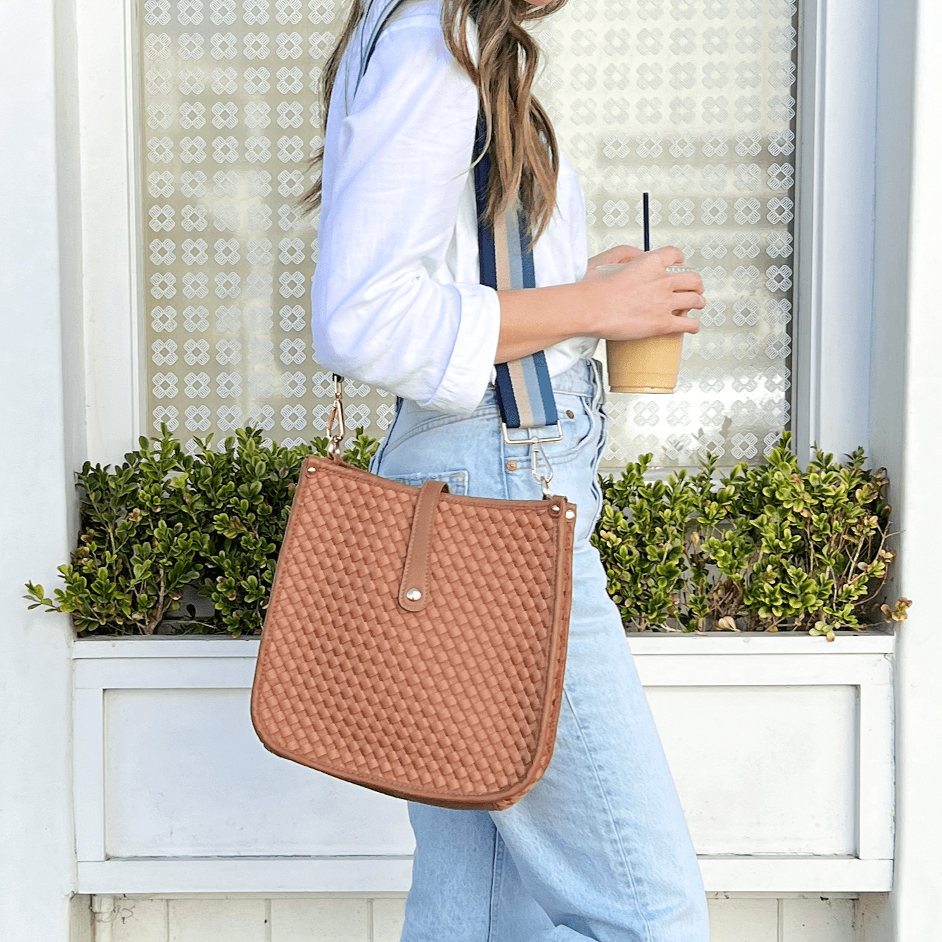 Woman carrying a brown woven neoprene courier bag with a striped interchangeable strap