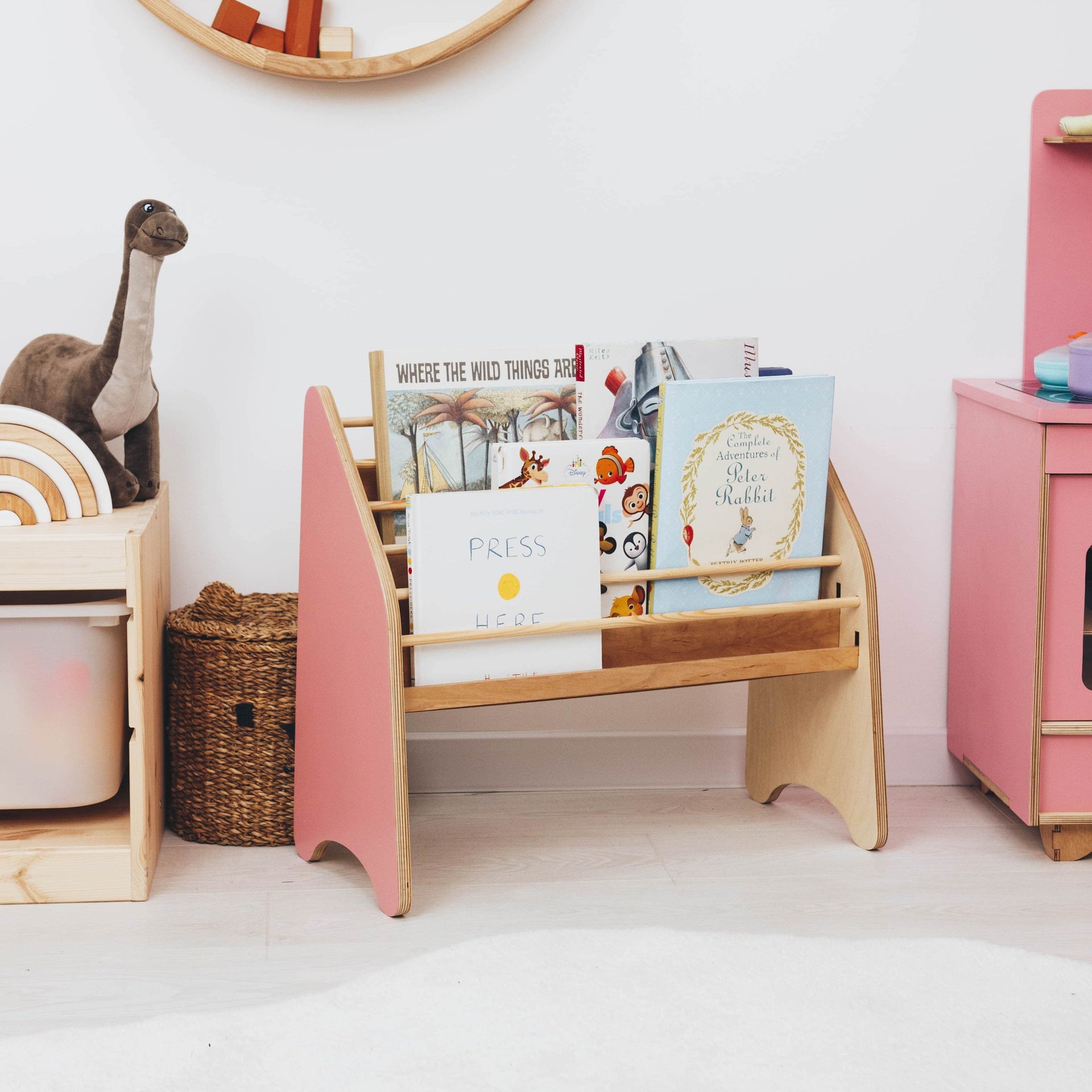 Pink Montessori bookshelf for toddlers placed in a nursery room