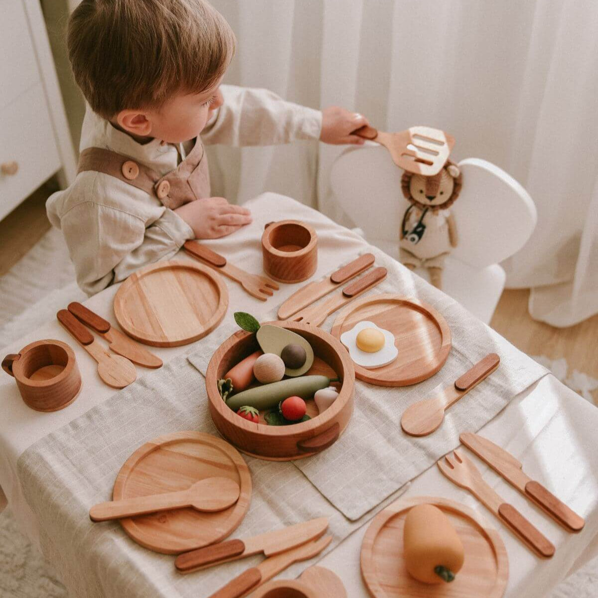 Wooden play kitchen dishes set arranged for a toddler pretend dinner party