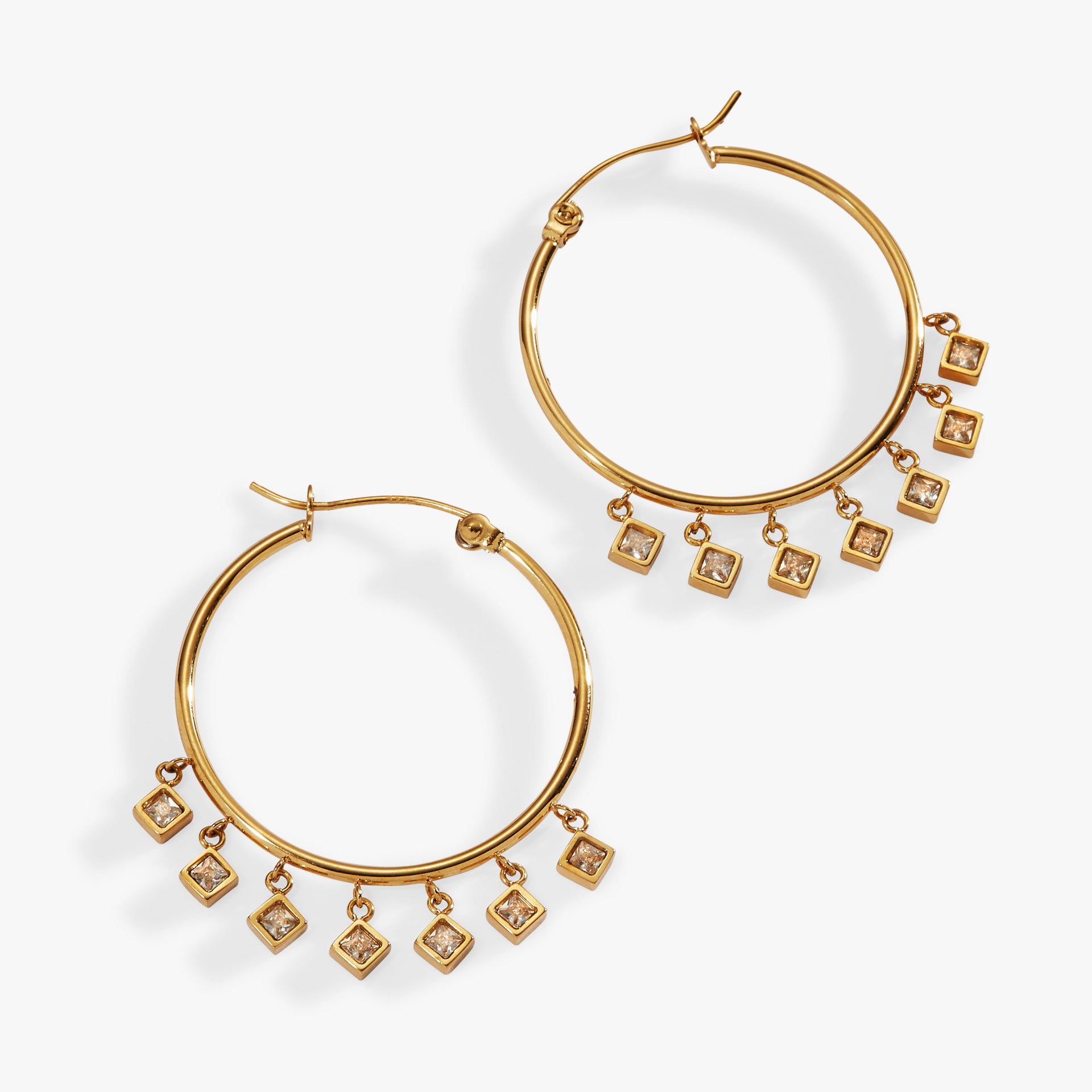 Princess cut crystal charms hanging from gold-tone stainless steel hoop earrings