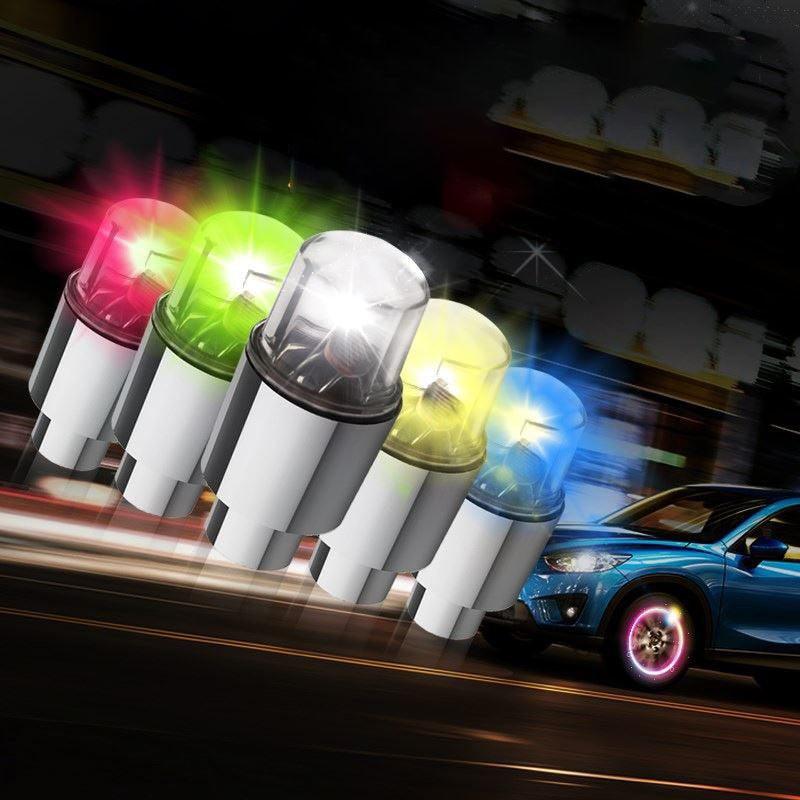 Metallic silver LED tire valve lights glowing with multi-colored neon light on a bicycle wheel