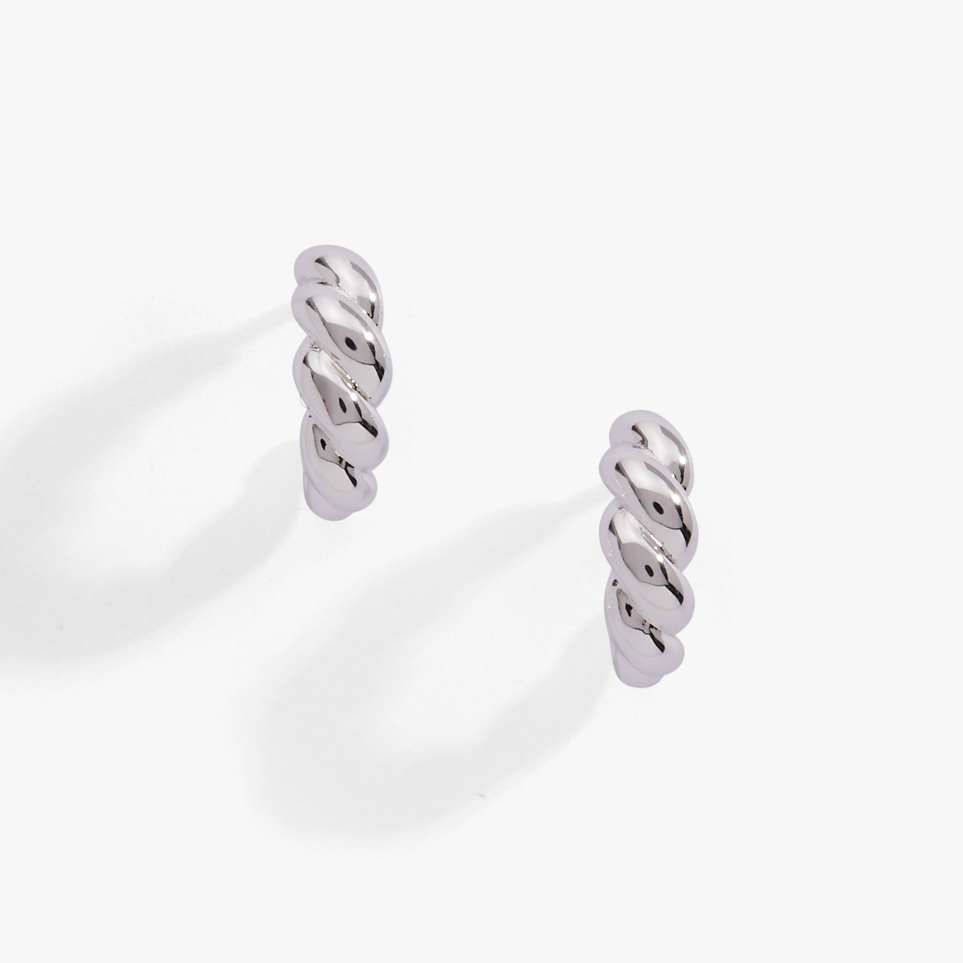 Close up of silver-plated puffy rope textured huggie hoop earrings