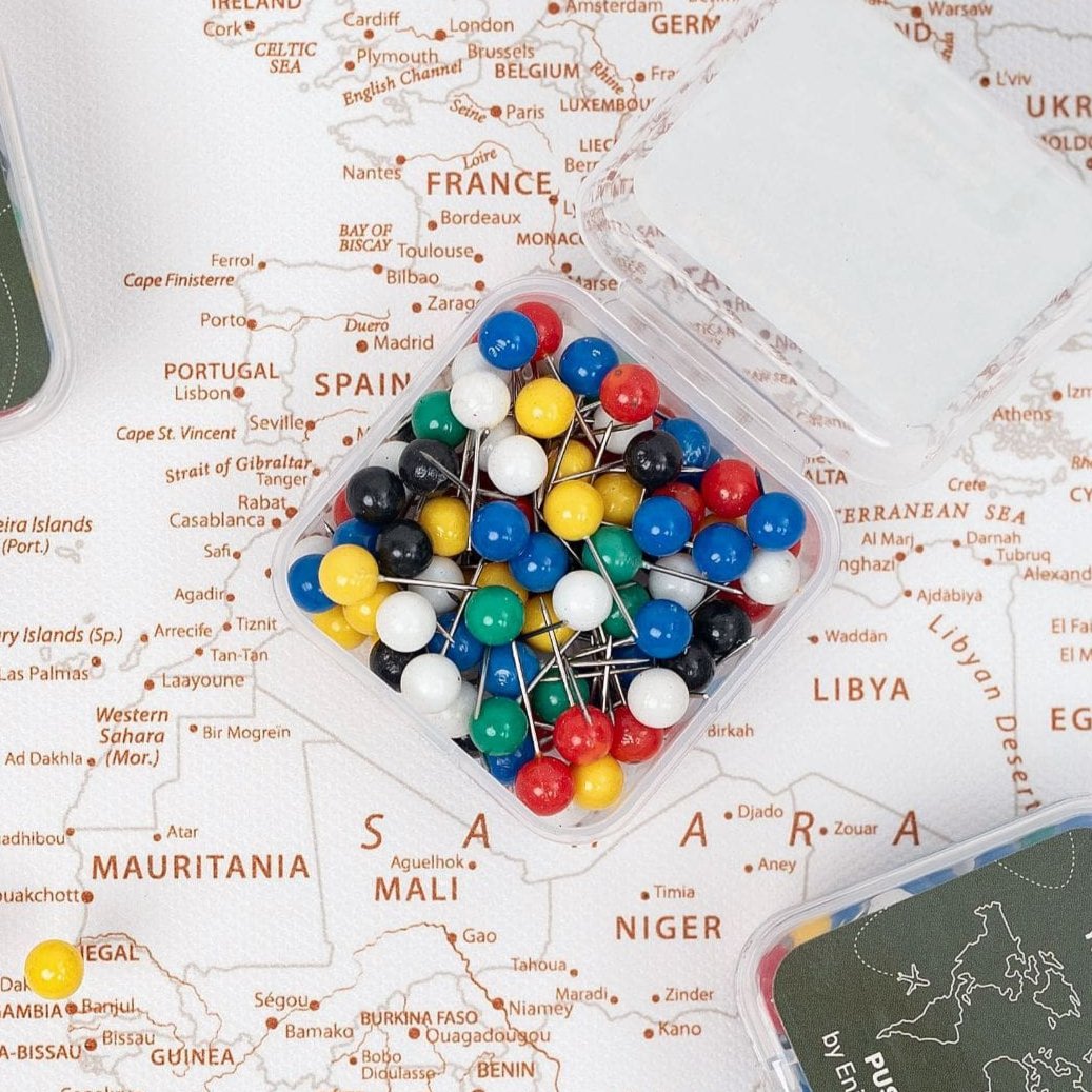 Close-up of multi-color decorative map push pins on a wooden surface.