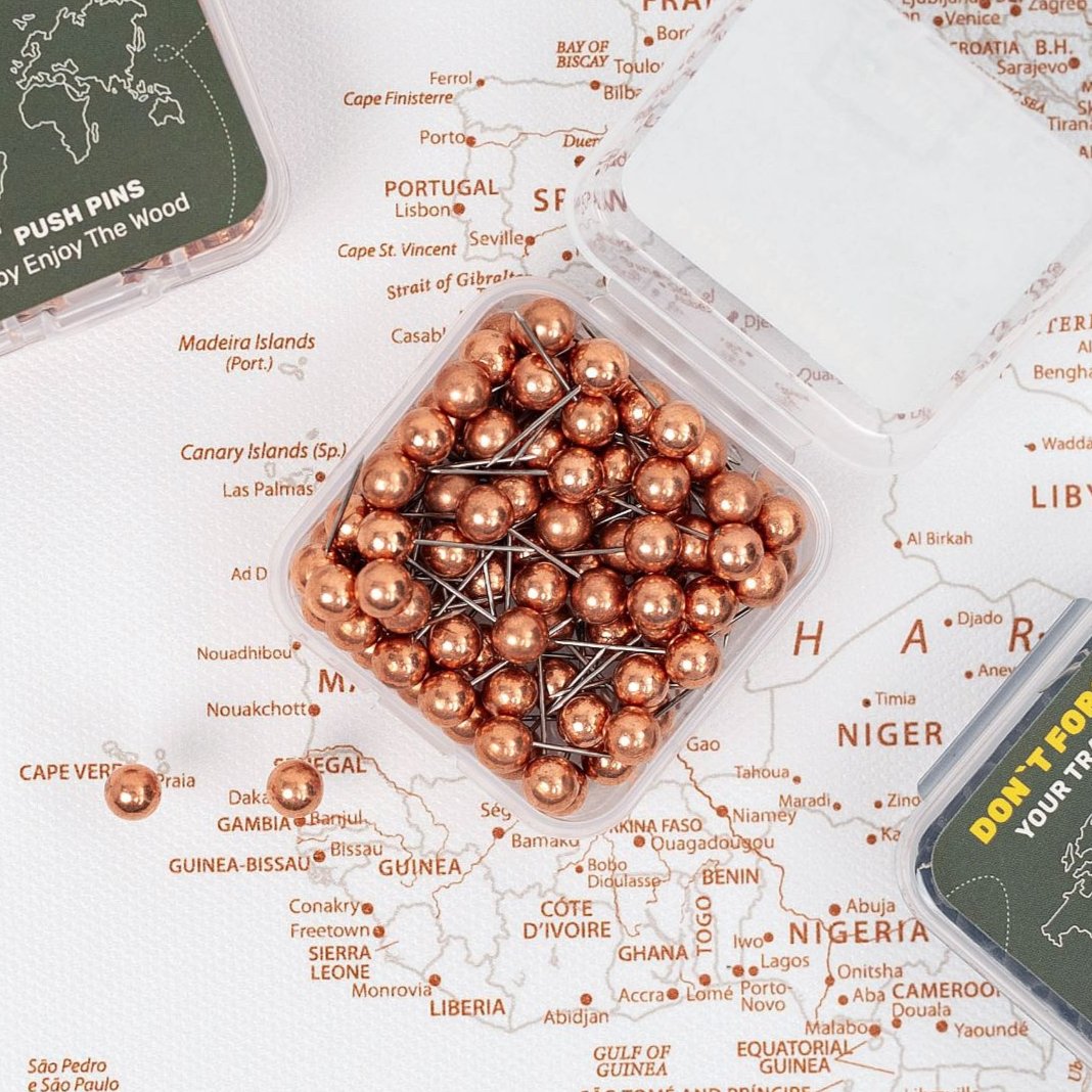 Set of delicate rose gold push pins placed on a canvas map
