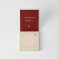 Pressed face powder in a minimalist compact, available in beige, tan, and brown.