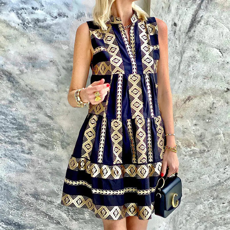A woman wearing a sleeveless mini dress with a navy and gold geometric print, featuring a tiered skirt design.